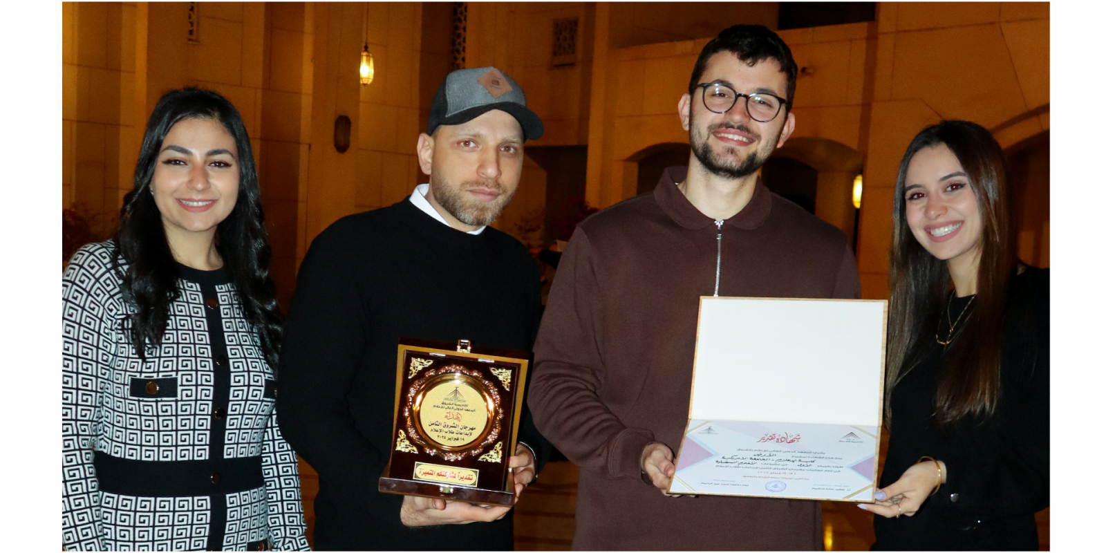 Two men and two women stand holding a plaque