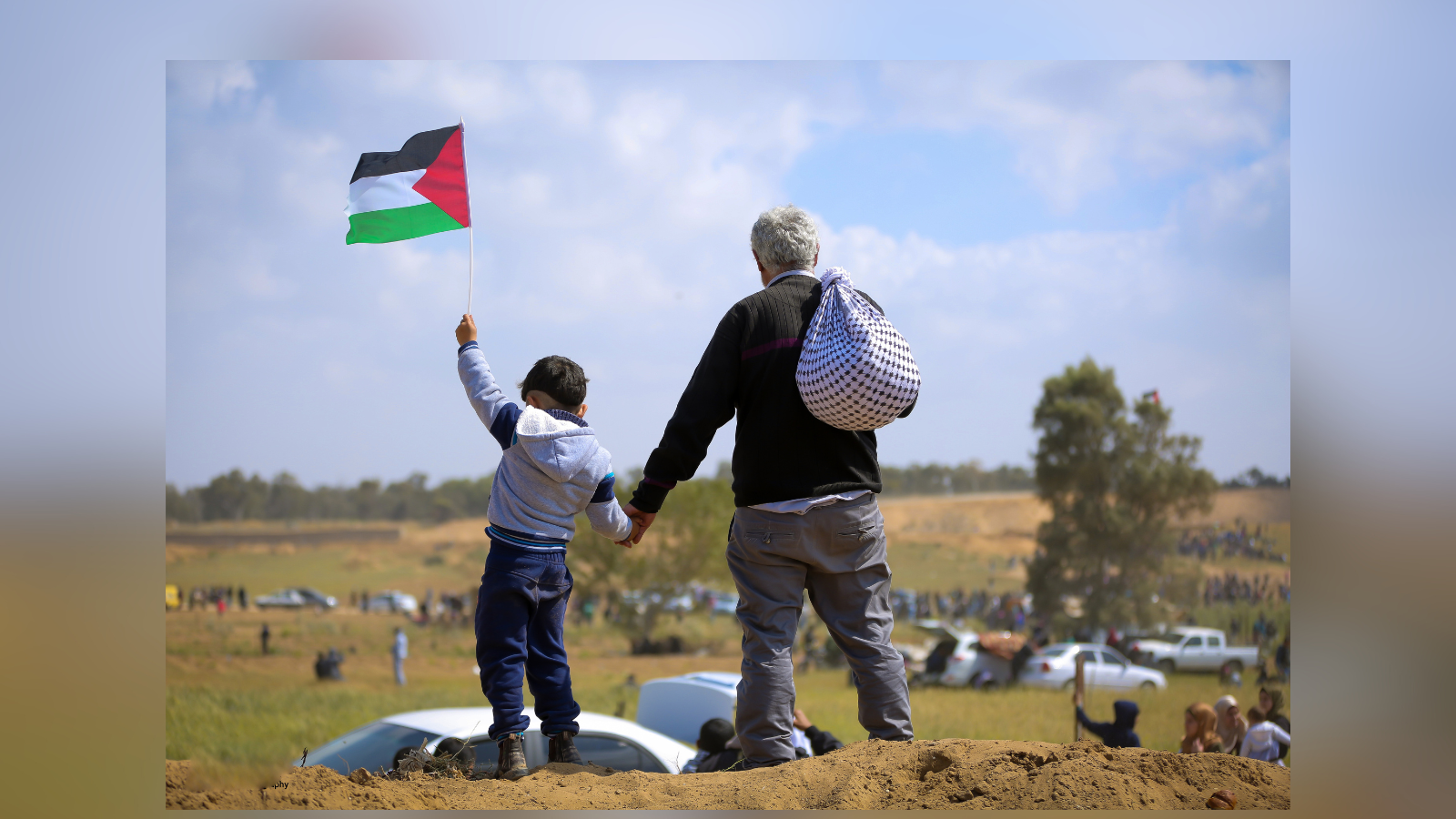 Boy holding Palestinian flag stands next to father