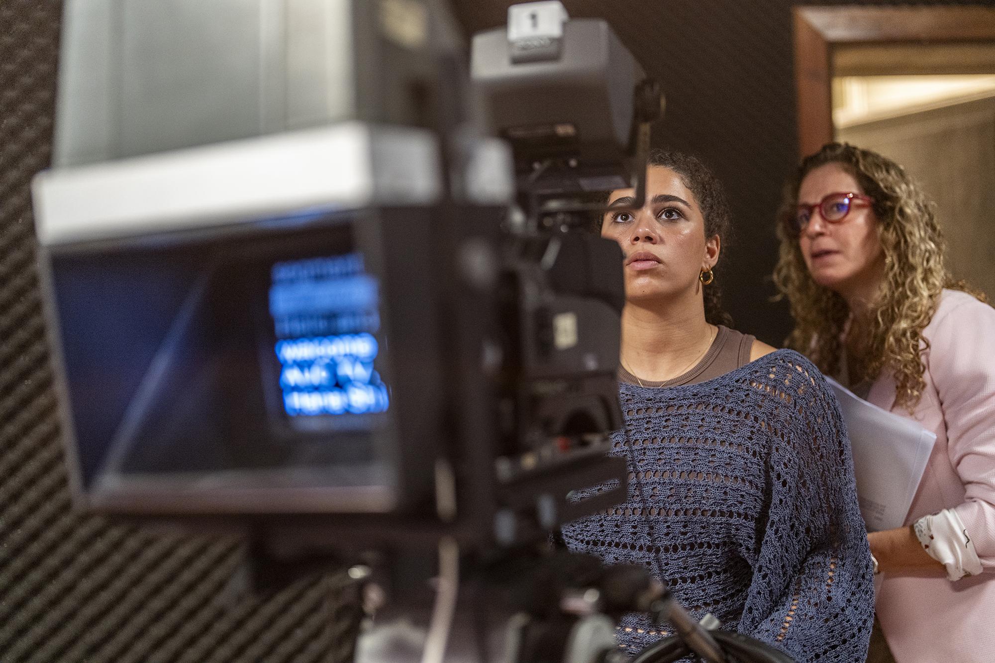 student working with filming camera with professor