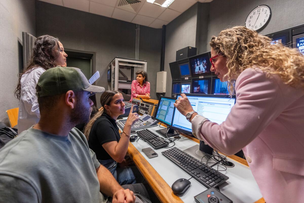students working with professor in studio media room