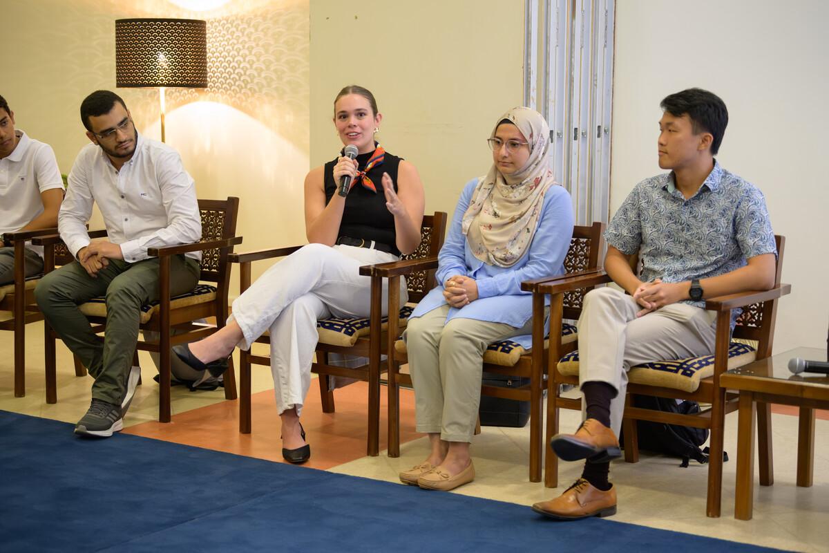 students in an event with one of the students with a microphone talking