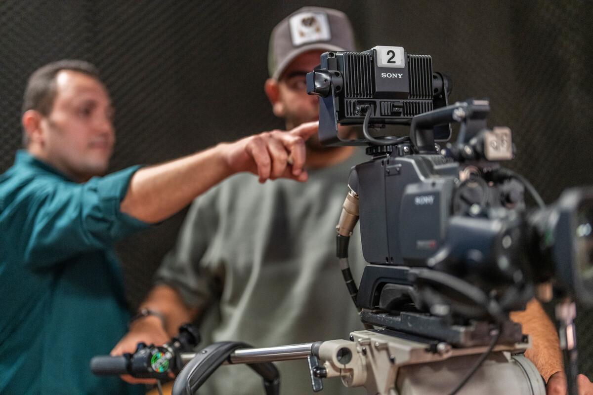 student working with instructor on how to use filming camera