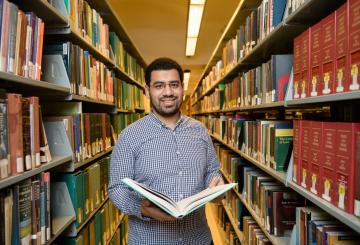 Student checking book shelves in a library