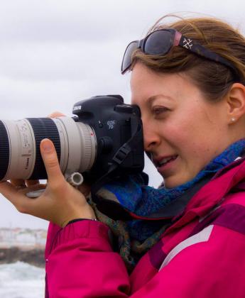 A woman is holding a big camera and looking into it