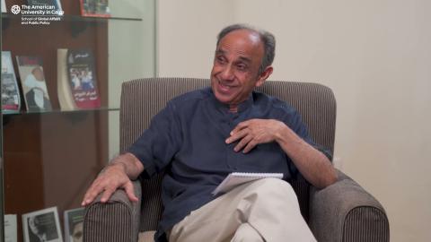 A man is sitting on a chair. HE is talking and smiling