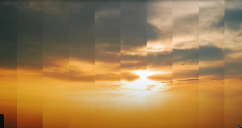 The sun rising in the sky amidst clouds