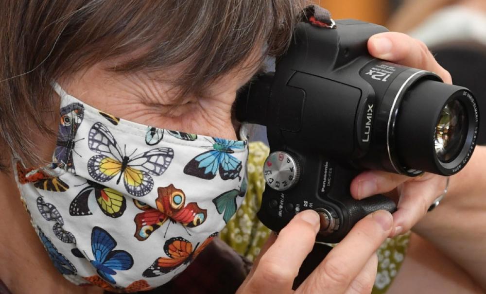 A masked woman holding a camera