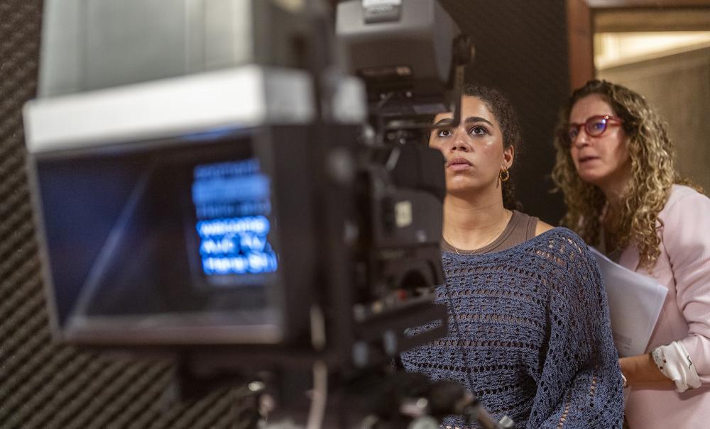 student working with filming camera with professor