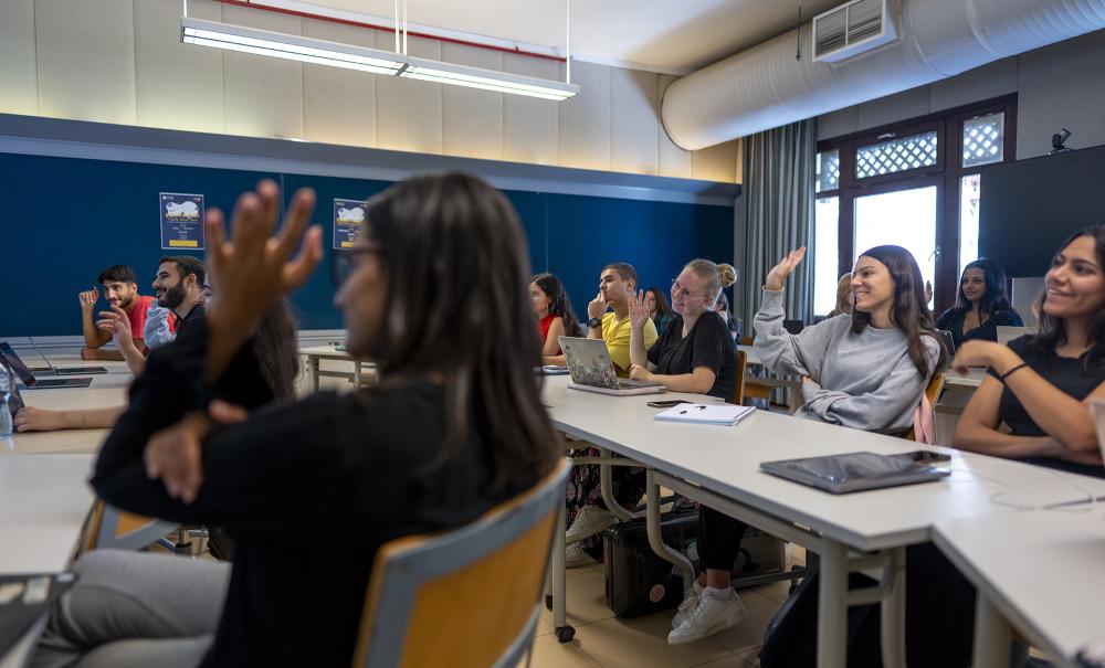 students raising their hands in class room in an interactive class discussion
