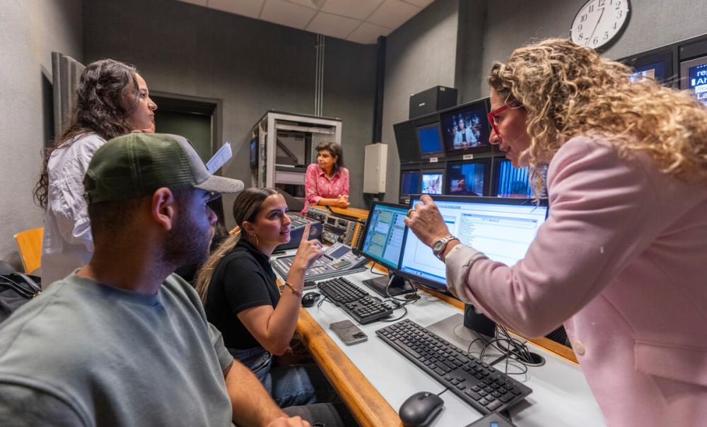 students working with professor in studio media room