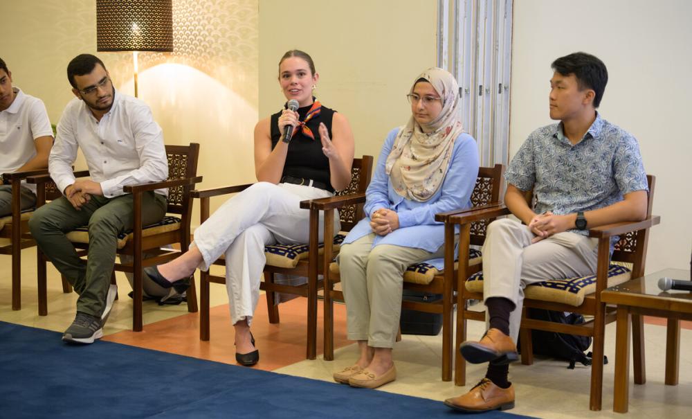 students in an event with one of the students with a microphone talking