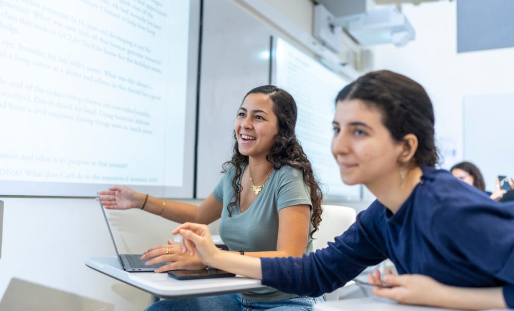students in classroom discussing topics on smart board