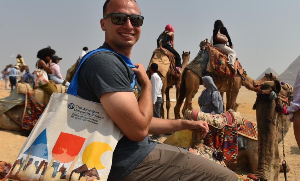 auc student with auc tote bag on a camel at the pyramids