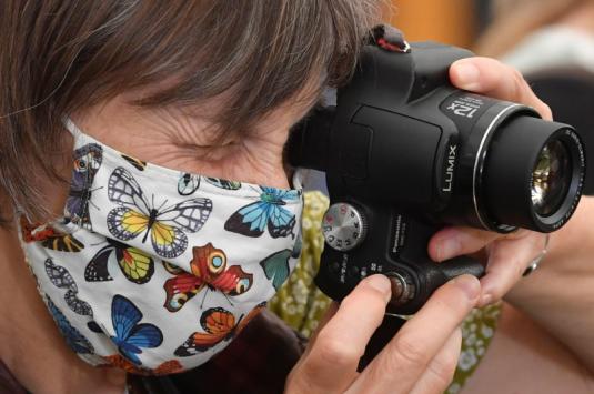 A masked woman holding a camera