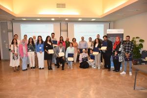 Males and females are standing together and smiling. Some of them are holding certificates