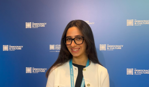 A picture of Laila Khalifa standing in front of a backdrop from the Athens Democracy Forum