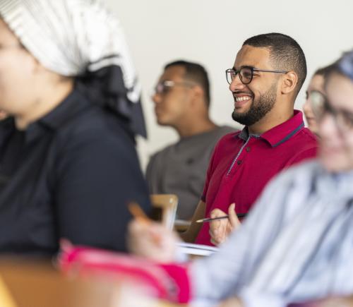 students smiling in class and taking notes