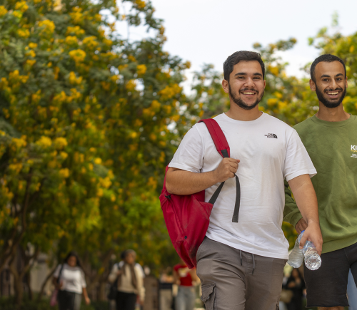 male students on campus smiling heading to class