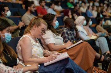 Graduate student taking notes in hall presenation