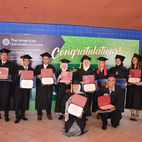  "Congratulations"Graduates holding their graduation certificates in front of a sign that reads
