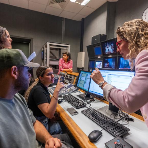 students working with professor in studio media room