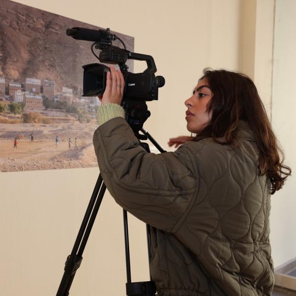 A female is adjusting a camera in an exhibition