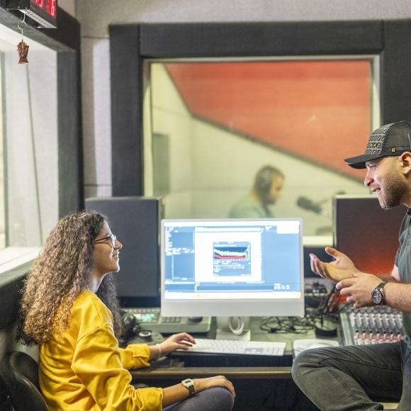professor with student working on digital equipment in studio